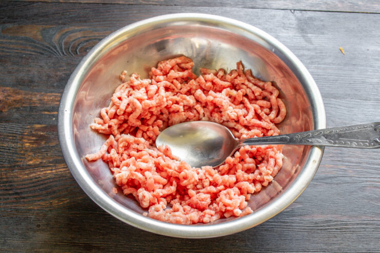 Preparing Freshly Ground Pork for Schnitzel - The Key to Juiciness Lean pork being processed through a meat grinder to make fresh mince.