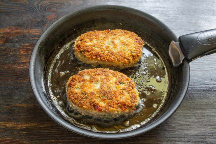 Finishing the Schnitzels in the Oven for Perfect Doneness Fried pork schnitzels on a baking sheet being placed into an oven.