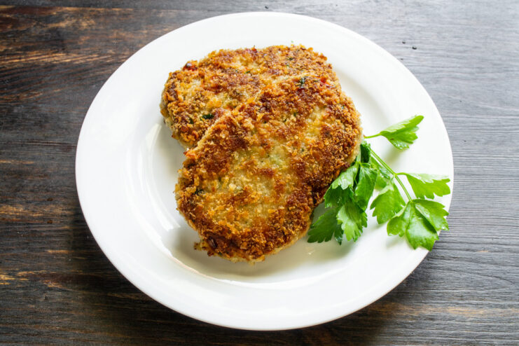 Hot and Juicy Pork Schnitzels Ready to Serve A plate of freshly cooked pork schnitzels with bell pepper, ready to be served.