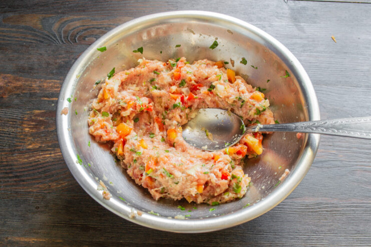 Chilling the Pork Mixture Before Forming Schnitzels A hand mixing the ground pork mixture in a bowl before chilling.