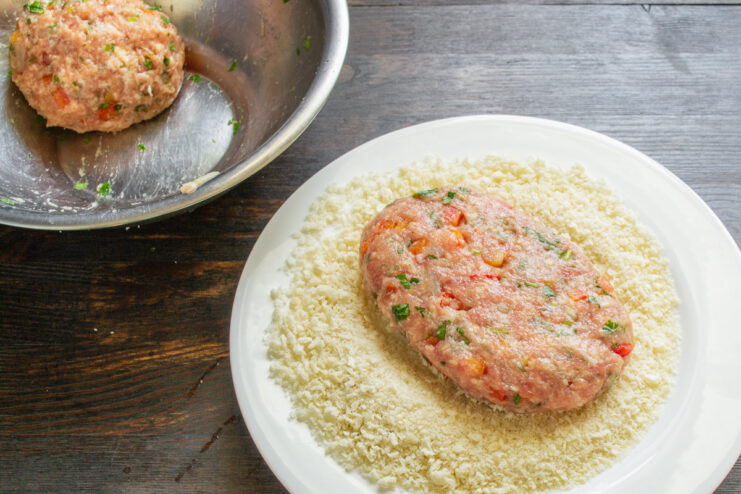 How to Form the Perfect Palm-Sized Pork Schnitzel A hand forming a raw pork schnitzel patty, about one centimeter thick.