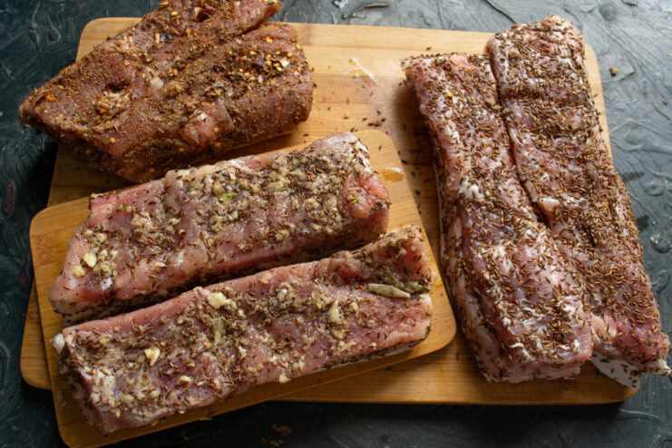 Spice Rub Variation 3: Toasted Caraway A piece of cured pork belly being coated in lightly crushed toasted caraway seeds.