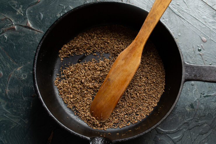 Step 9: Toasting Caraway Seeds for the Spice Rub Caraway seeds being toasted in a black cast-iron skillet.