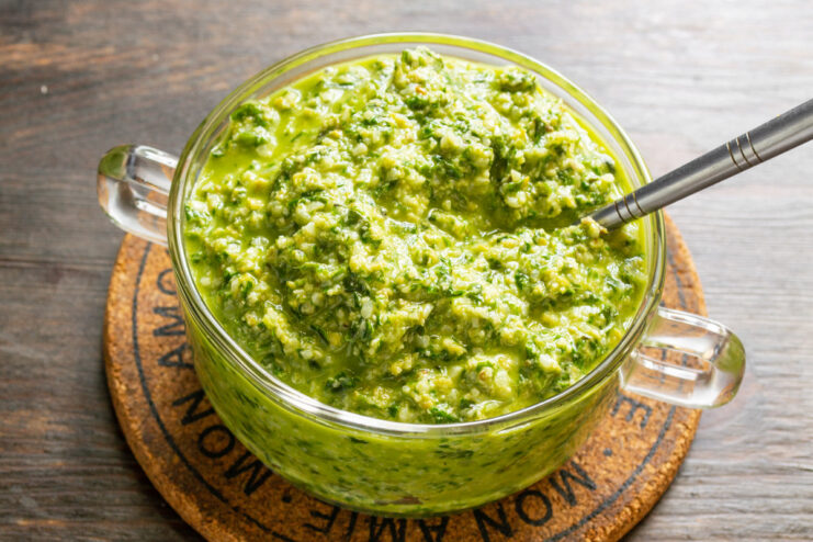 Storing homemade olive pesto in an airtight jar A jar of freshly made green pesto with olives, sealed for storage in the refrigerator.