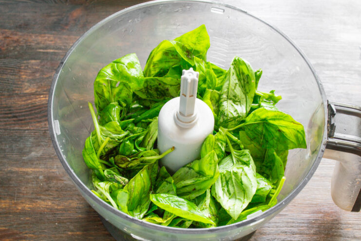 Adding fresh basil leaves to a blender for pesto Dried basil leaves being placed into the bowl of a food processor.