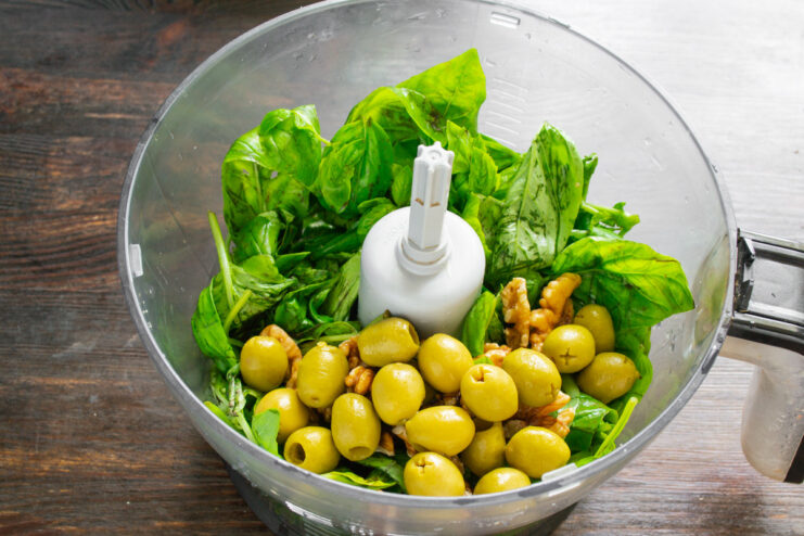 Adding green olives for a unique, tapenade-like pesto Pitted green olives being added to the blender with other pesto ingredients.