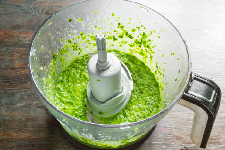 Blending the pesto sauce to a smooth consistency The pesto ingredients being blended into a smooth, vibrant green sauce in a blender.