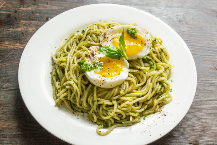 Final plating of Spaghetti with Pesto and Egg The finished dish: spaghetti with pesto topped with a halved soft-boiled egg, black pepper, and a fresh basil leaf.