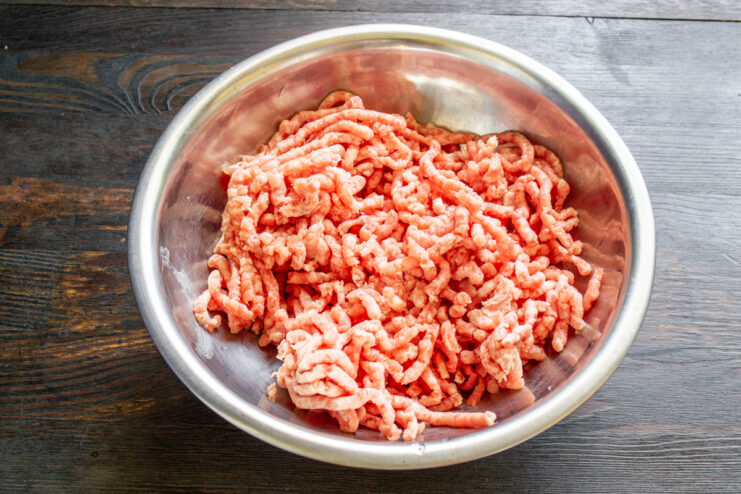 Starting with lean ground meat for a healthier soup base. A package of fresh lean ground meat on a wooden cutting board.