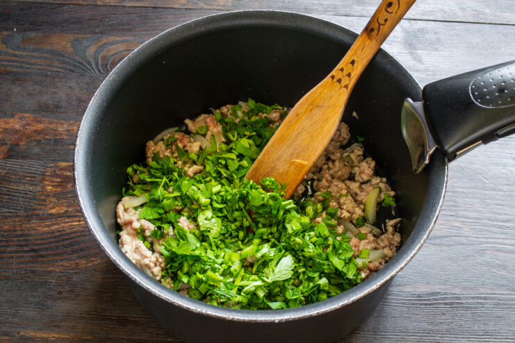 Adding fresh parsley for a burst of vibrant flavor. Finely chopped fresh parsley being added to the browned ground meat in the pot.