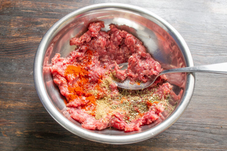 Step-by-step guide to making flavorful meatballs for soup A bowl of ground beef with spices and crushed walnuts, ready to be mixed for meatballs.