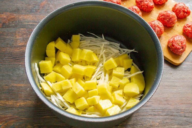 Dicing potatoes for a hearty soup base Diced raw potatoes in a pot, ready for cooking.