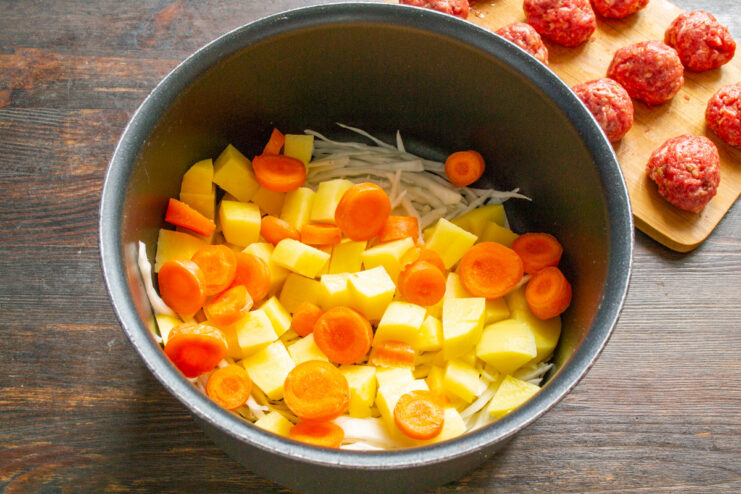 Slicing carrots to add sweetness and color to the soup Sliced carrots being added to a pot with other vegetables.