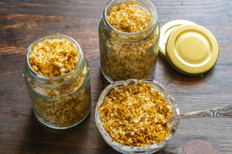 Storing Homemade Svanetian Salt for Freshness Finished Svanetian salt being spooned into a small, clean glass jar with an airtight lid.