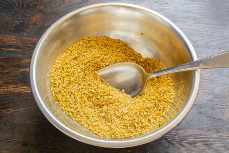 Mixing the Salt and Spices for Even Distribution A spoon mixing a blend of ground spices and coarse salt in a white bowl.