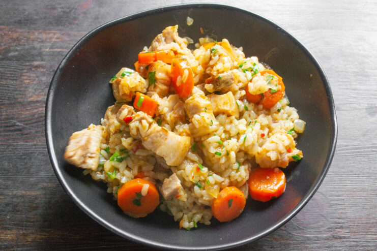 Serving Suggestion: Garnish with Fresh Herbs and Serve Hot A serving of pork belly with rice and vegetables on a plate, garnished with fresh herbs.