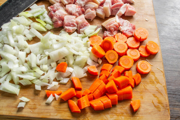 Preparing Carrots for the Aromatic Rice Dish A carrot being peeled and sliced into thick rounds on a cutting board.