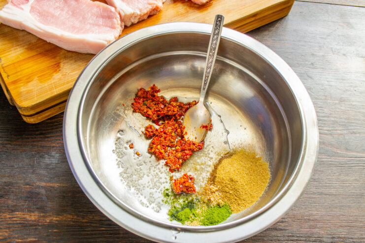 Step 2: Preparing the Marinade with Adjika and Spices A bowl with marinade ingredients: red pepper adjika, dried dill, and mustard powder.