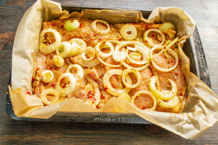 Step 6: Layering Onions and Pork in a Baking Dish Layering marinated onions and pork loin chops in a parchment-lined baking dish.