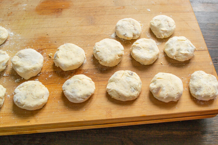 Shaped Syrniki Ready for Frying on a Floured Board Shaped, uncooked ricotta syrniki arranged on a floured cutting board.