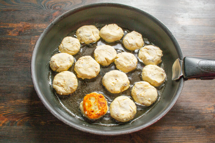 Frying Ricotta Syrniki in a Hot Pan Placing uncooked ricotta syrniki into a hot frying pan with shimmering oil.
