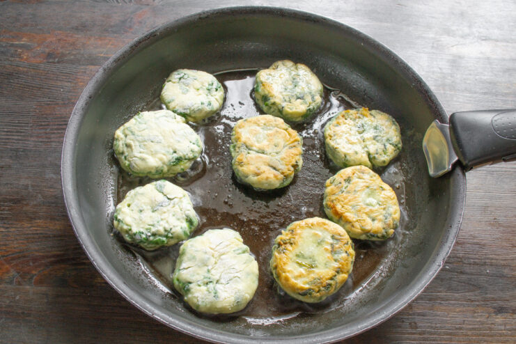 Frying the syrniki to achieve a perfect golden crust. Round syrniki frying in a black pan with oil until golden brown.
