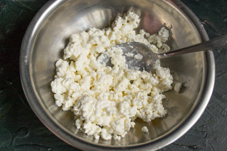 Preparing the base for Syrniki with grained tvorog A bowl of grained tvorog, the main ingredient for the syrniki batter.