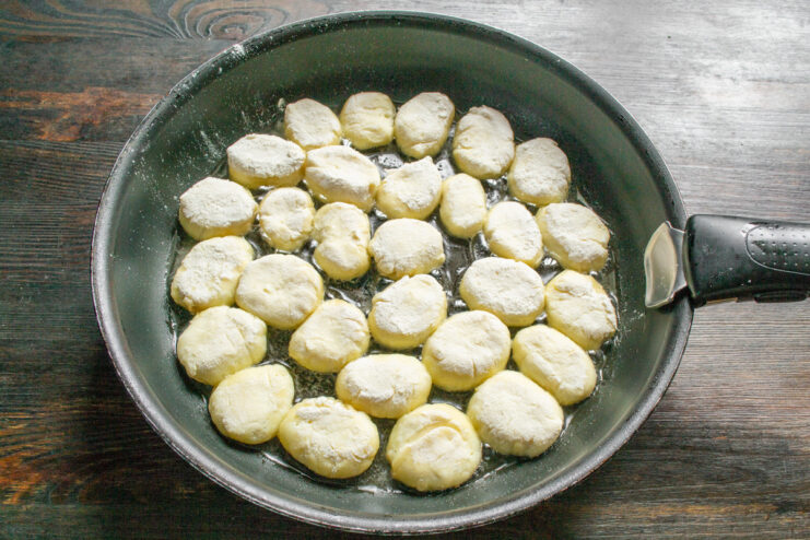 Frying the syrniki in a hot pan Placing uncooked syrniki into a hot skillet with oil.