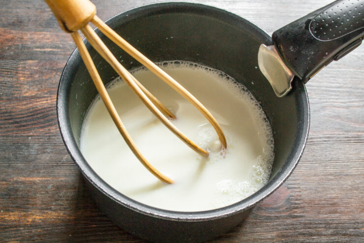 Heating the milk for the custard Pouring milk into a stainless steel saucepan to heat for the custard.