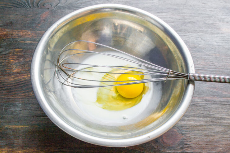 Preparing the Egg Wash for Golden Pastries A bowl with milk and a cracked egg, ready to be mixed for an egg wash.