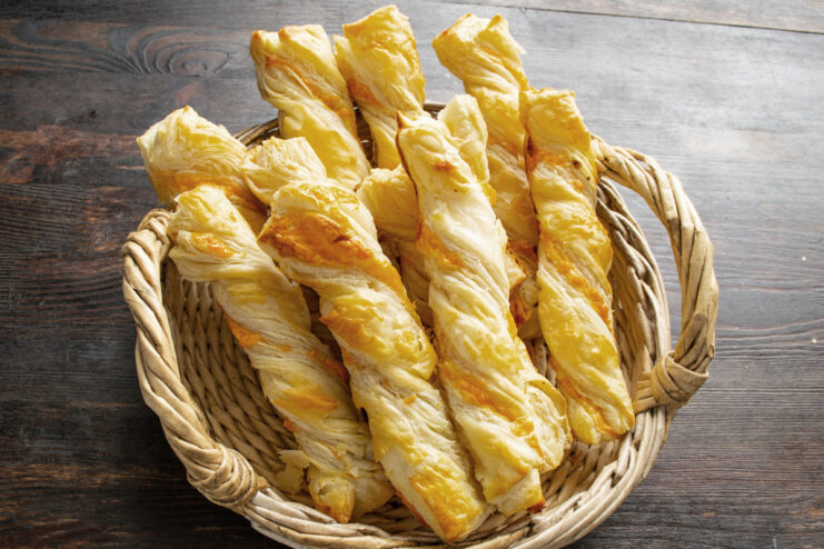 Enjoying Warm and Savory Cheese Sticks A close-up of freshly baked, golden puff pastry cheese sticks on a plate.