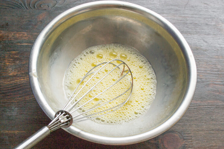 Whisking the Egg and Milk for a Perfect Glaze A hand whisking an egg and milk mixture in a white bowl.