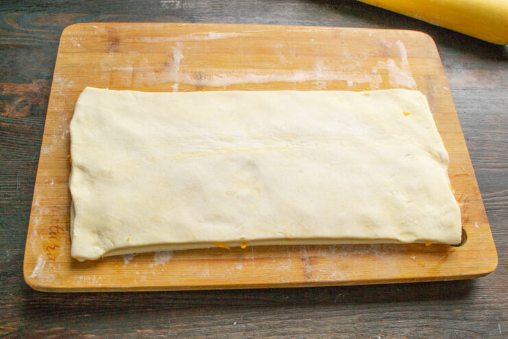 Assembling the Cheese-Filled Pastry Sandwich A second sheet of puff pastry being placed over the cheese-covered layer.