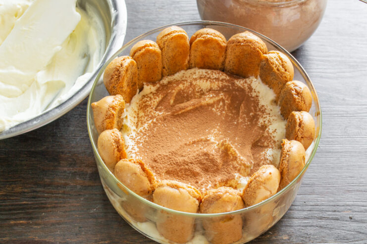 Dusting a layer of Tiramisu cream with cocoa powder using a small sieve.