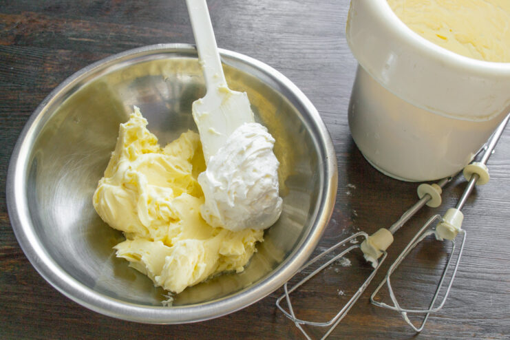 Folding whipped cream into a bowl of mascarpone mixture with a spatula.
