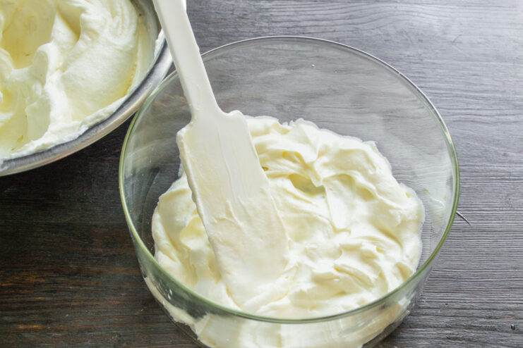 Spreading a layer of mascarpone cream on the bottom of a glass dish.