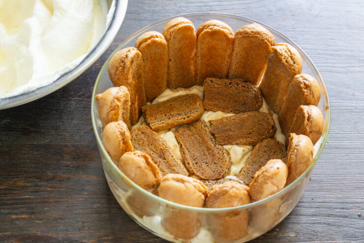 Placing coffee-soaked ladyfinger offcuts onto the cream base inside the Tiramisu.