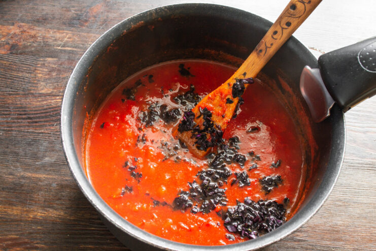 Preparing Fresh Purple Basil for the Finishing Touch A hand holding a bunch of fresh purple basil leaves, ready for chopping.