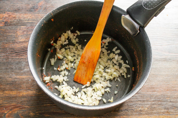 Adding Diced Onions for a Flavorful Base Finely diced white onion in a clean saucepan, ready for cooking.