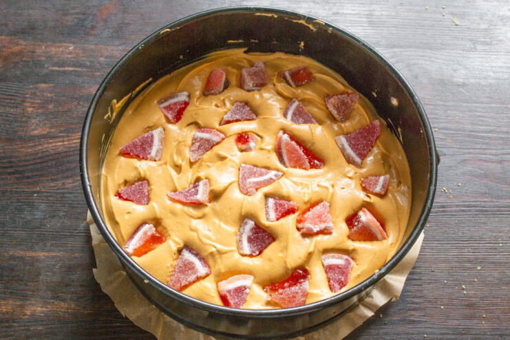Step 8: Adding Fruit Jelly Candy Pieces Pieces of colorful fruit jelly candy being pressed into the caramel cream layer of the cake.