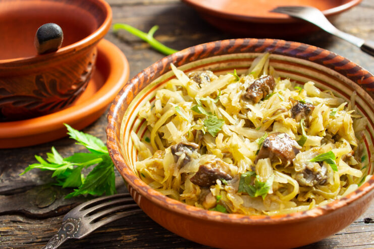A bowl of freshly made braised cabbage with wild mushrooms, garnished with fresh herbs.
