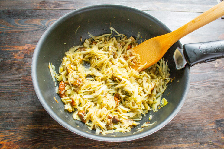 Braised cabbage and mushrooms cooking in an uncovered skillet to reduce liquid.