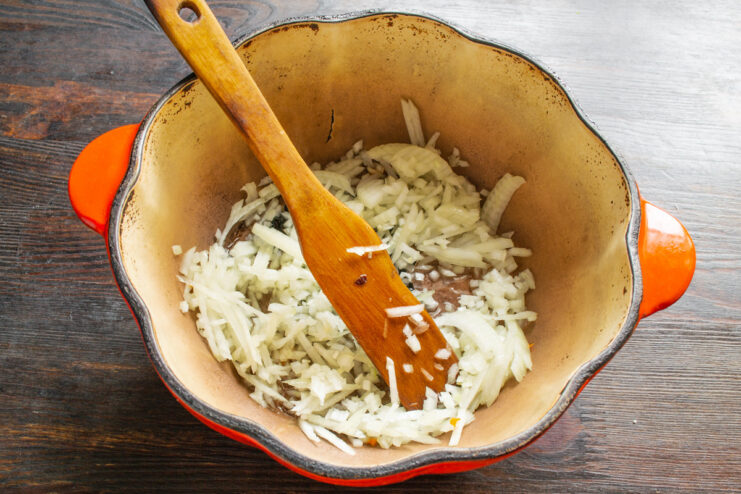 Sautéing Onions and Garlic for a Flavorful Base Chopped onions and garlic being sautéed in a Dutch oven until fragrant and translucent.