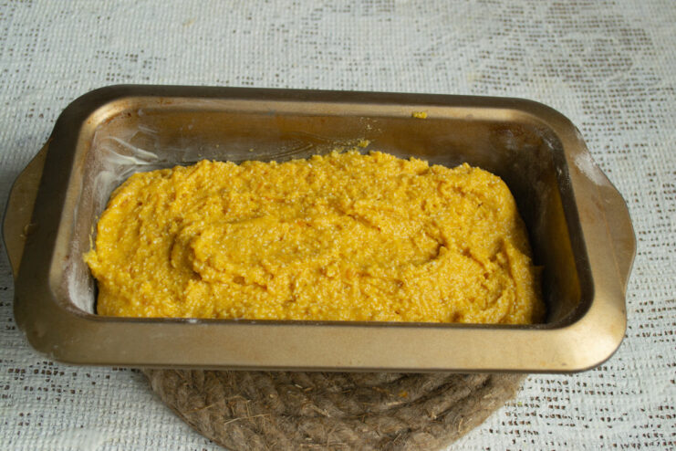 Pouring the Batter into the Prepared Loaf Pan The thick pumpkin cake batter being poured and spread into a prepared loaf pan.