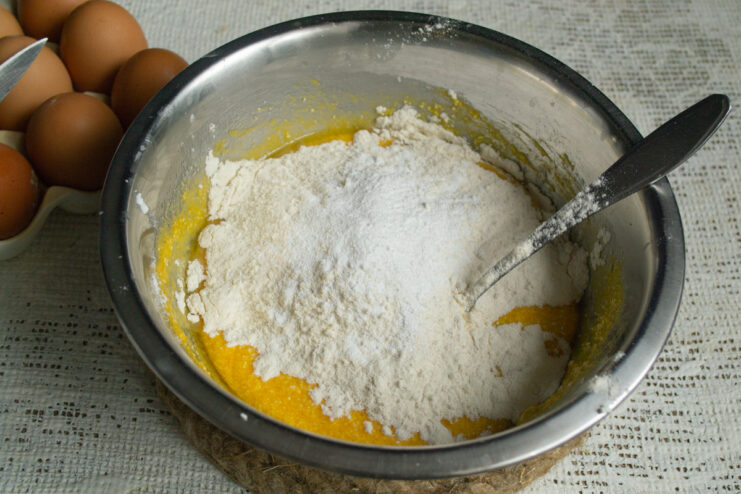 Sifting Flour into the Wet Ingredients Sifting all-purpose flour into a bowl of wet ingredients for the pumpkin loaf cake.