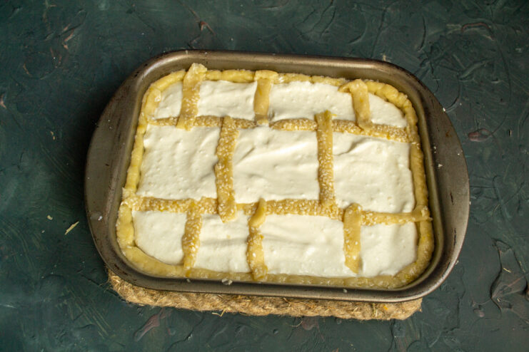 Creating a beautiful lattice top for the Tvorog pie. Decorating the top of the cottage cheese pie with a lattice pattern made from dough strips.