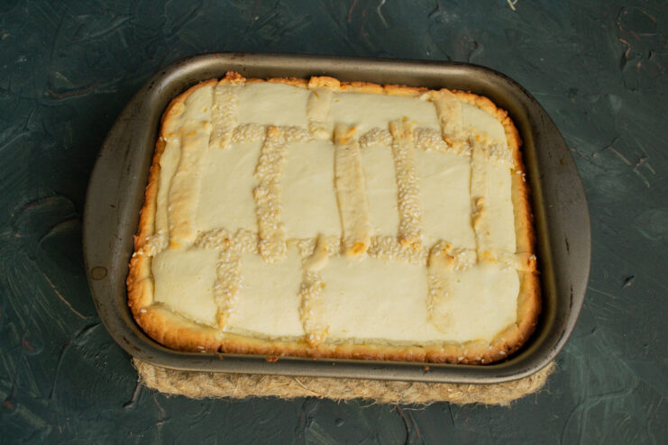 Baking the pie to golden perfection in a preheated oven. The assembled Tvorog pie with a lattice top, ready to be baked in the oven.