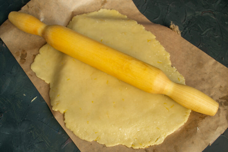 Pro tip: Roll the delicate dough on parchment paper for easy transfer. Rolling out the pie dough thinly on a sheet of parchment paper with a wooden rolling pin.