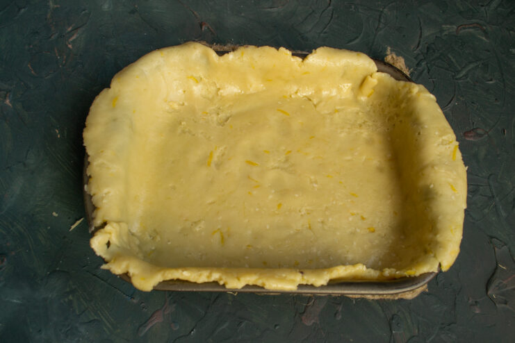 How to line the baking dish with the delicate vegetable oil dough. Placing the rolled-out dough on parchment paper into a rectangular baking dish.