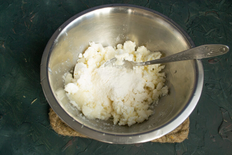 Adding sweetness and structure: Mixing sugar and flour into the filling. Adding sugar and flour to the cottage cheese and lemon juice mixture in a bowl.